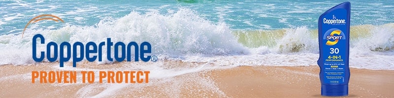 Coppertone Sport sunscreen bottle on sandy beach, ready for travelers staying active by the ocean during their trip.