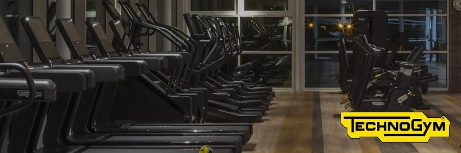 Modern gym with Technogym equipment, including treadmills and bikes, perfect for staying fit while traveling. Logo bottom right.